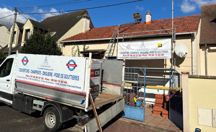 Camion benne de l'entreprise devant un pavillon en cours de rénovation de toiture