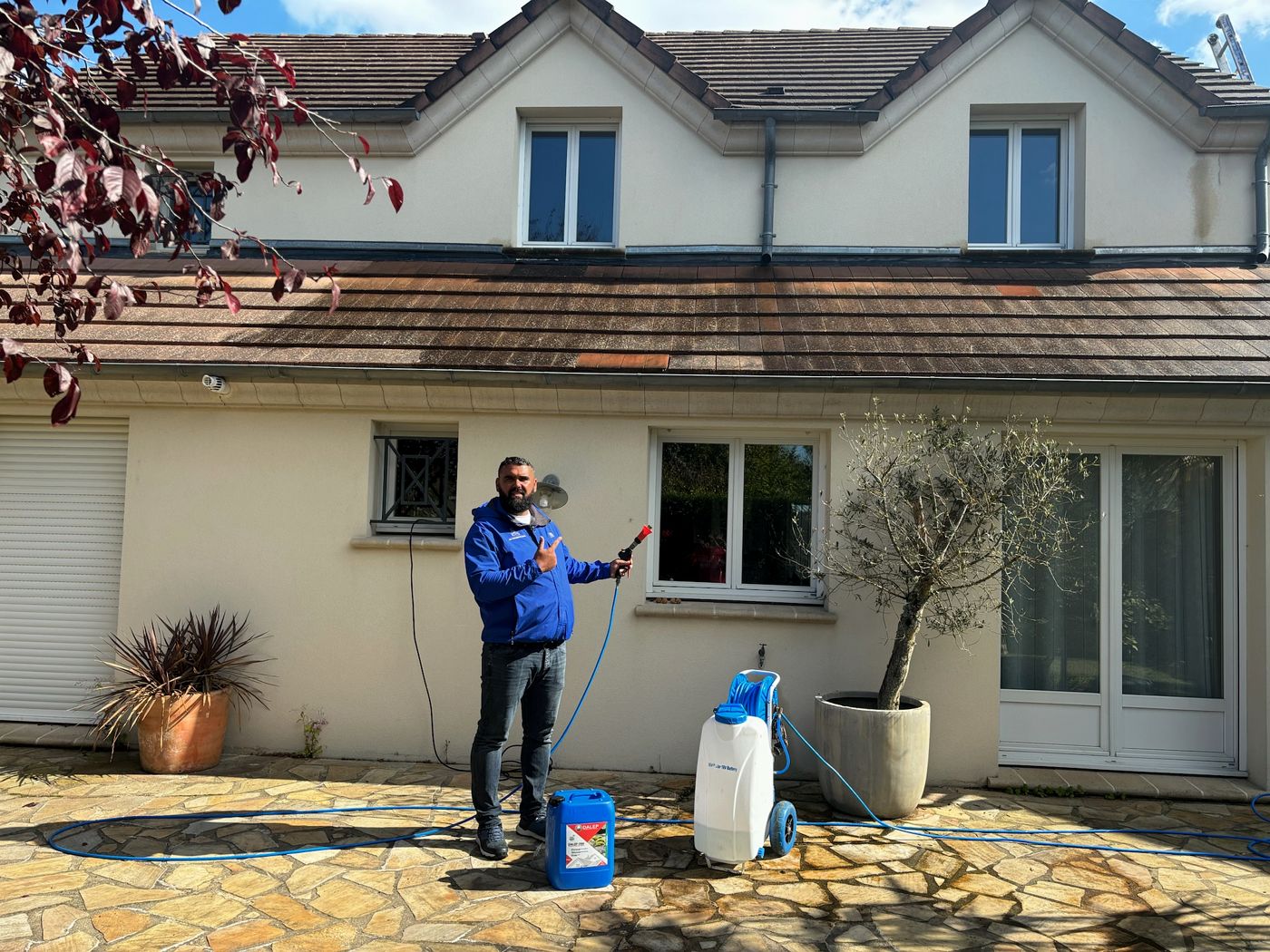 Kevin Paumard avec le pulvérisateur et le bidon de traitement hydrofuge sur la terrasse d'un pavillon à Nozay