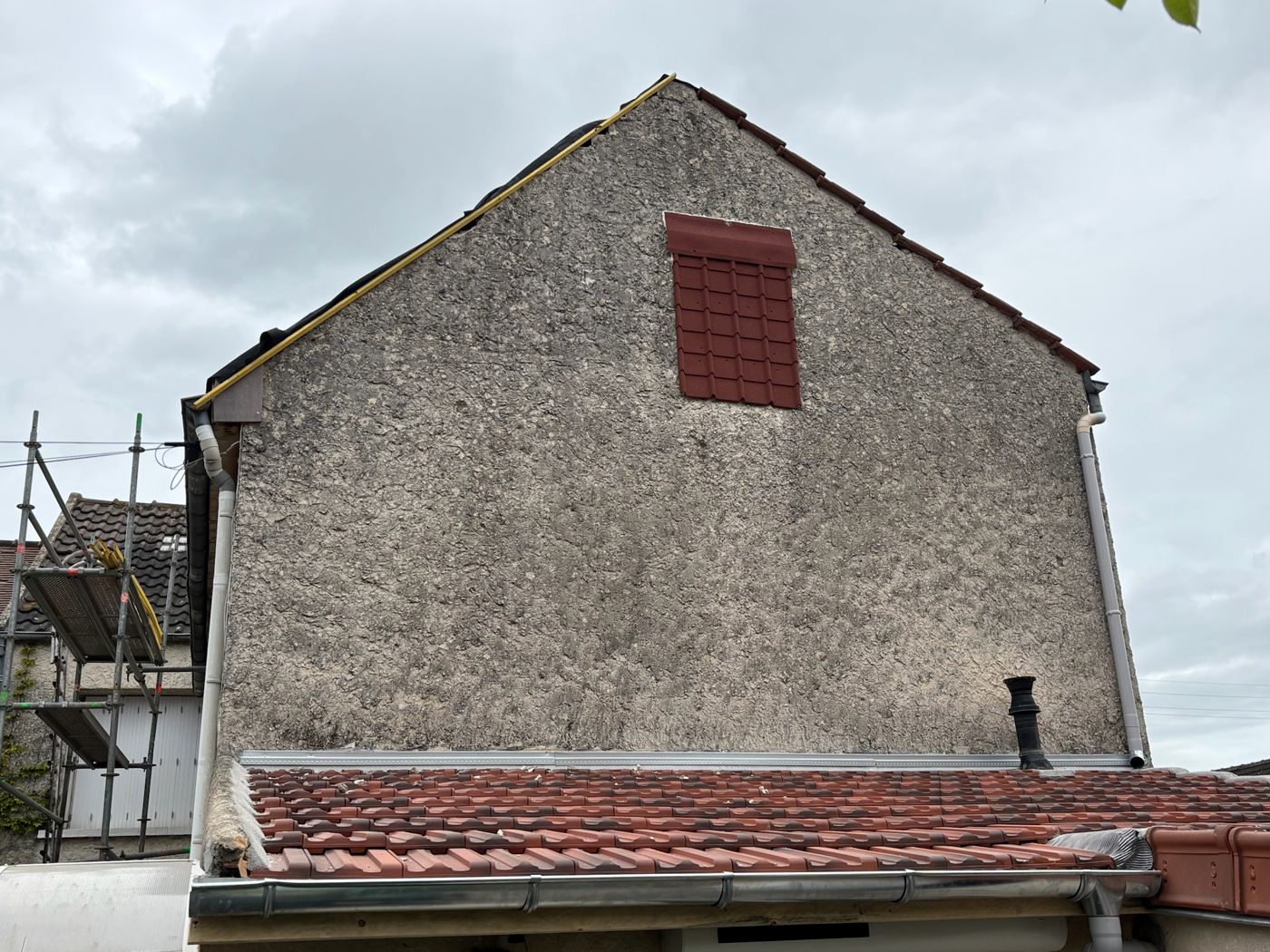Pignon de la maison avec sa rive reprise et toiture neuve de l'extension en contrebas, à La Norville