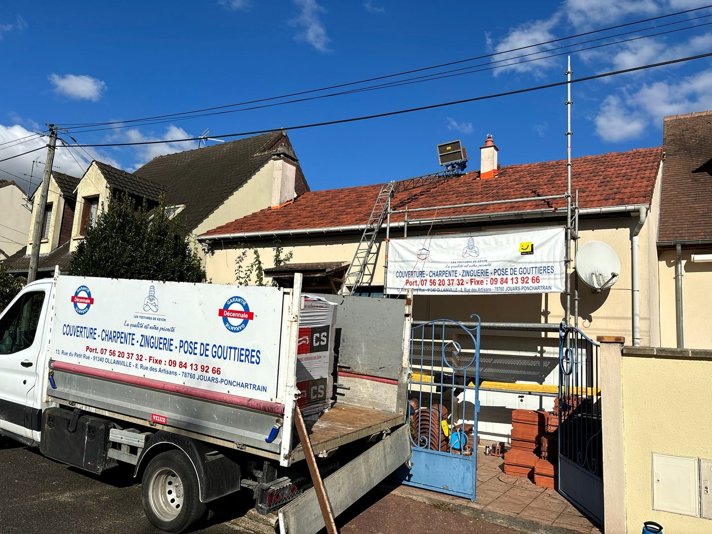 Tuiles neuves livrées derrière le portail et échafaudage contre la façade d'une maison à Bures-sur-Yvette