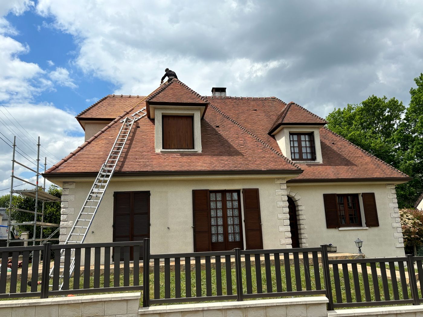 Maison à lucarnes couverte de tuiles plates à Palaiseau, un couvreur au faîtage, échelle et échafaudage en place