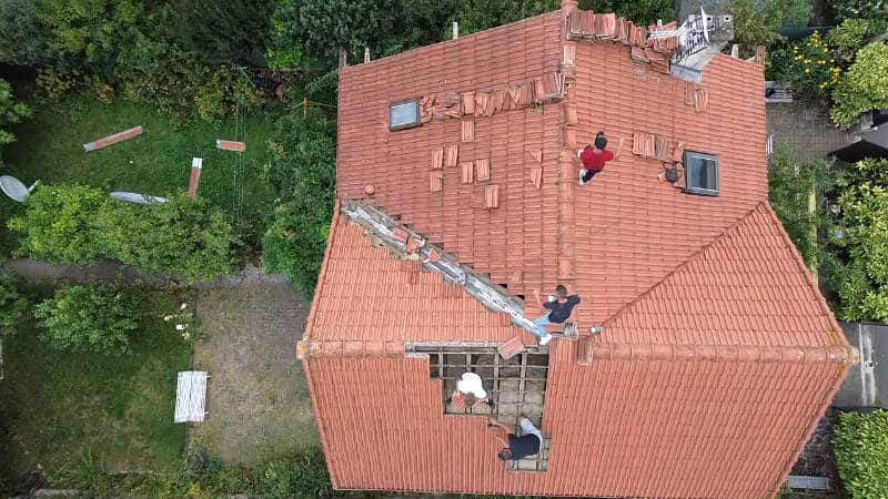 Vue aérienne de la pose de tuiles neuves lors d'une rénovation en Essonne
